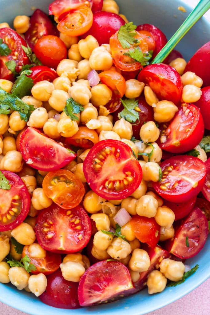 closeup of cherry tomato chickpea salad in blue bowl. 