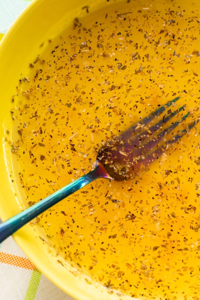 fork mixing dressing in yellow bowl.