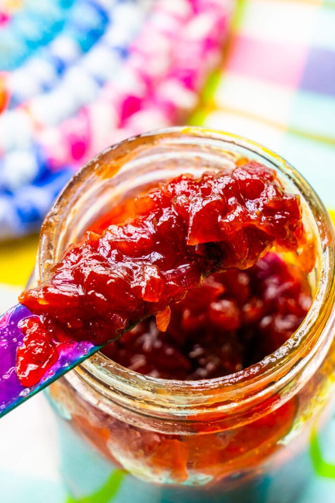 mason jar filled with red onion jam with knife scooping it out.