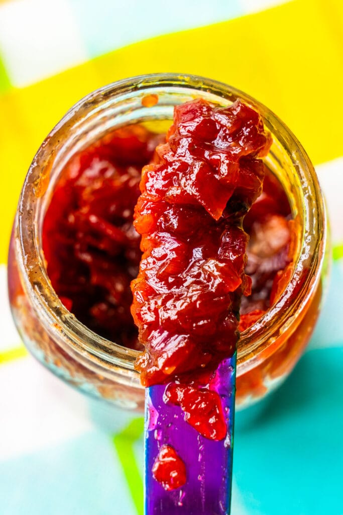 red onion jam in mason jar with knife scooping it out.