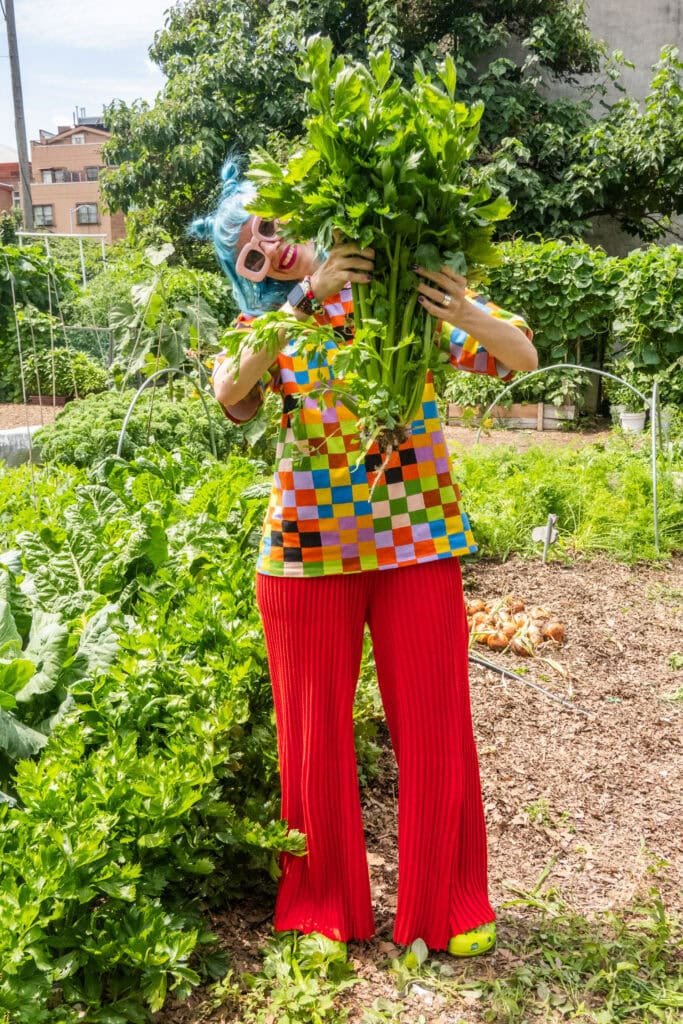 pamela of brooklyn farm girl holding celery up in her nyc garden.