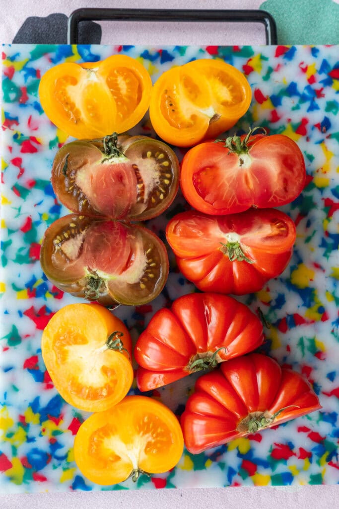 beautiful heirloom tomatoes cut in half on cutting board.