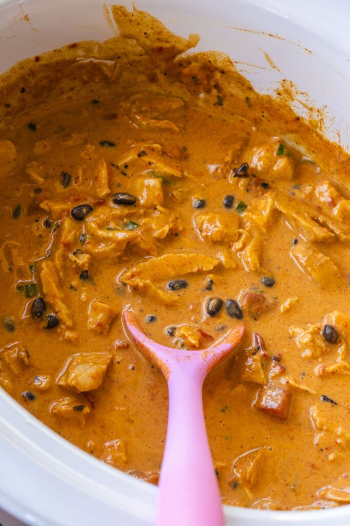 pink spoon stirring cheese dip.