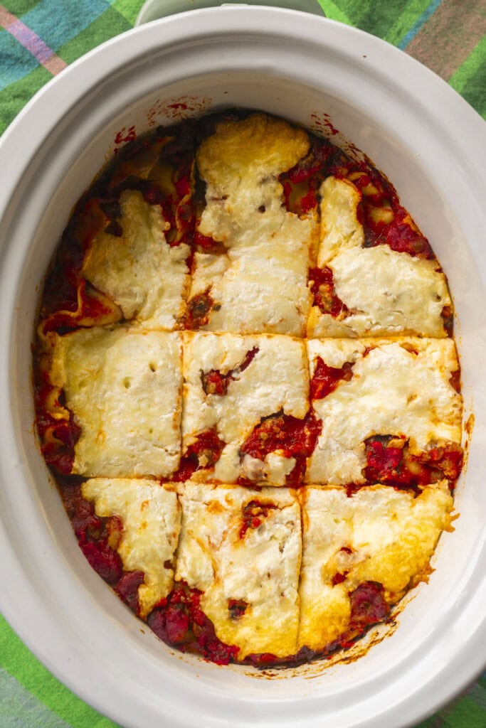 lasagna cut up into slices in the crockpot.