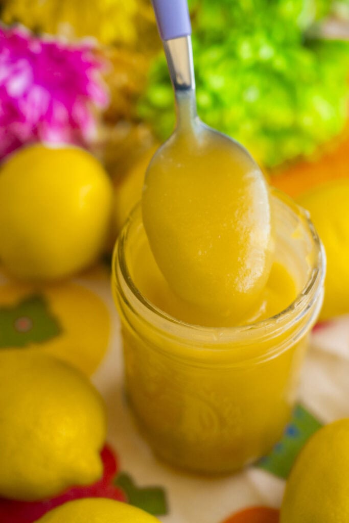 spoon lifting out lemon curd from mason jar.