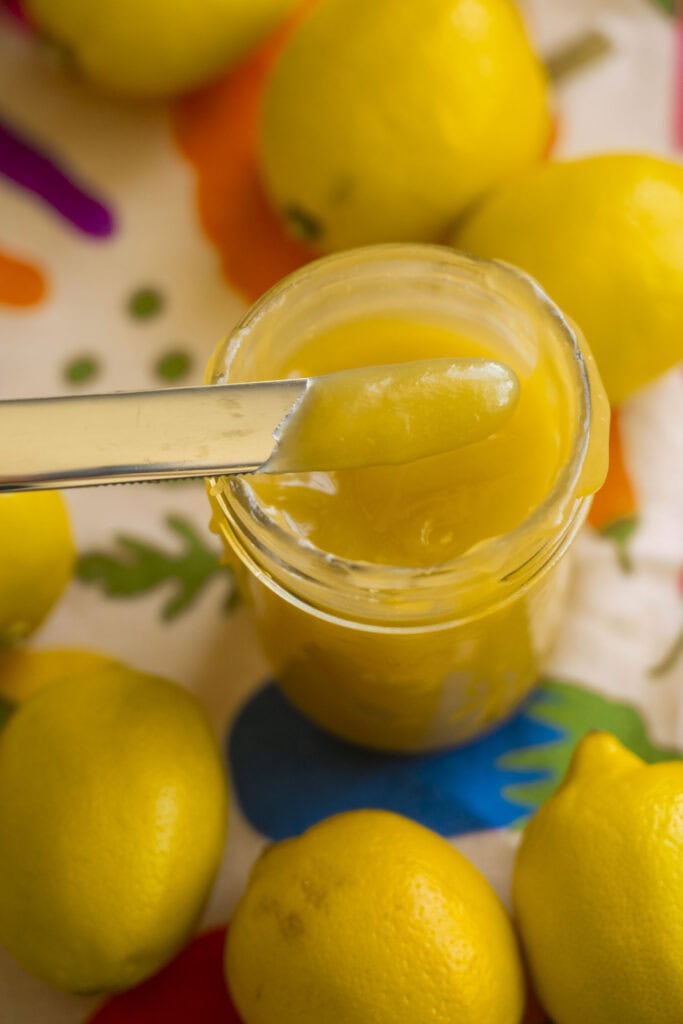 butter knife lifting out lemon curd from mason jar.