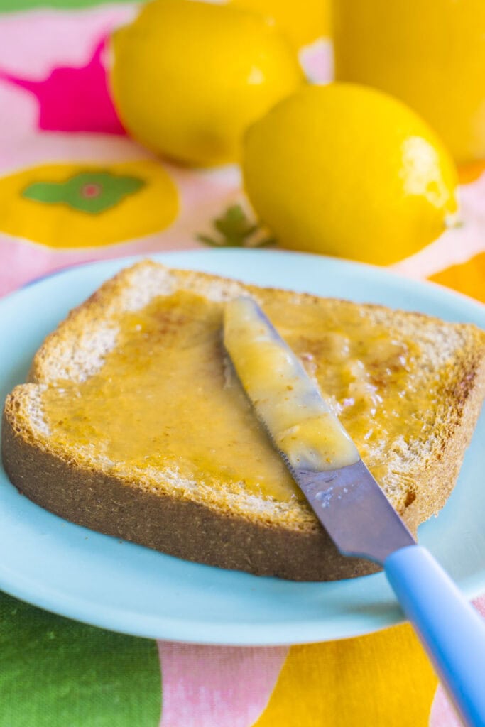 knife spreading on lemon curd onto toast.