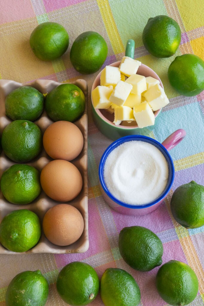 limes, sugar, butter and eggs on table with plaid table cloth.