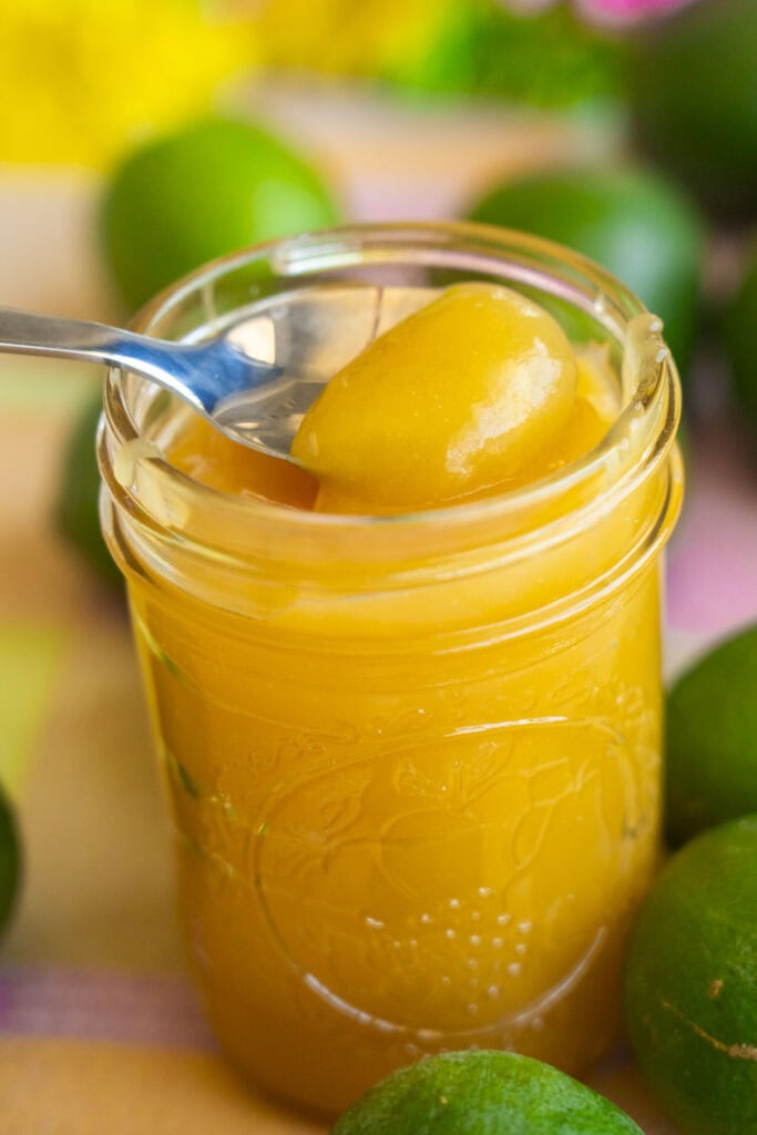 spoon lifting out lime curd from mason jar.