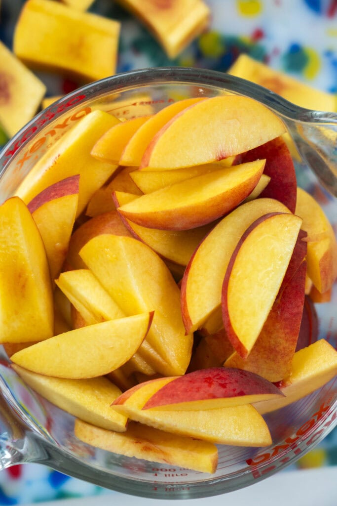 large bowl filled with fresh peach slices in it. 