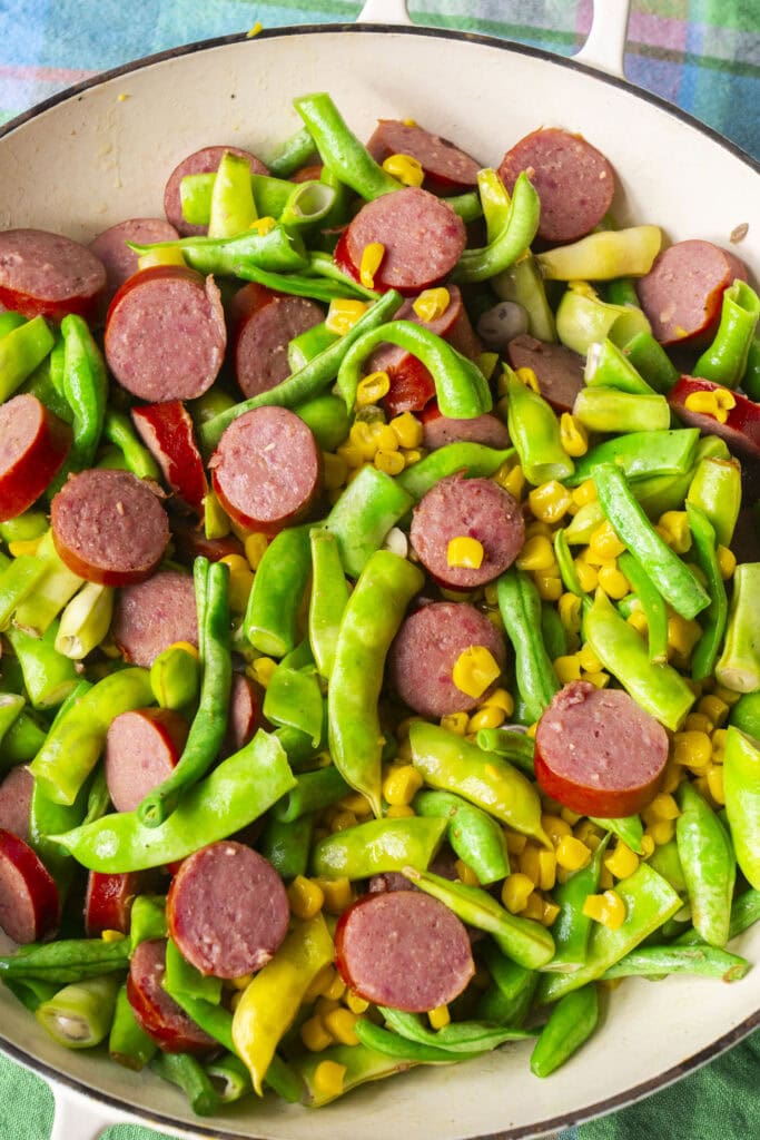 skillet filled with kielbasa, green beans and corn.