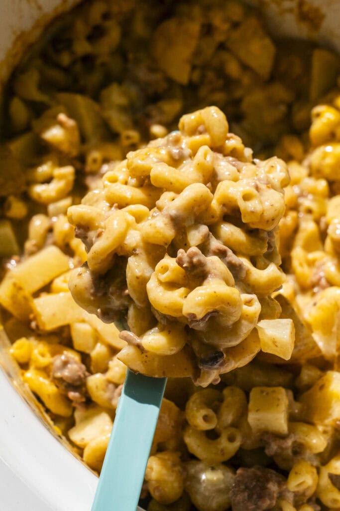 spoon serving hamburger helper out of crockpot.