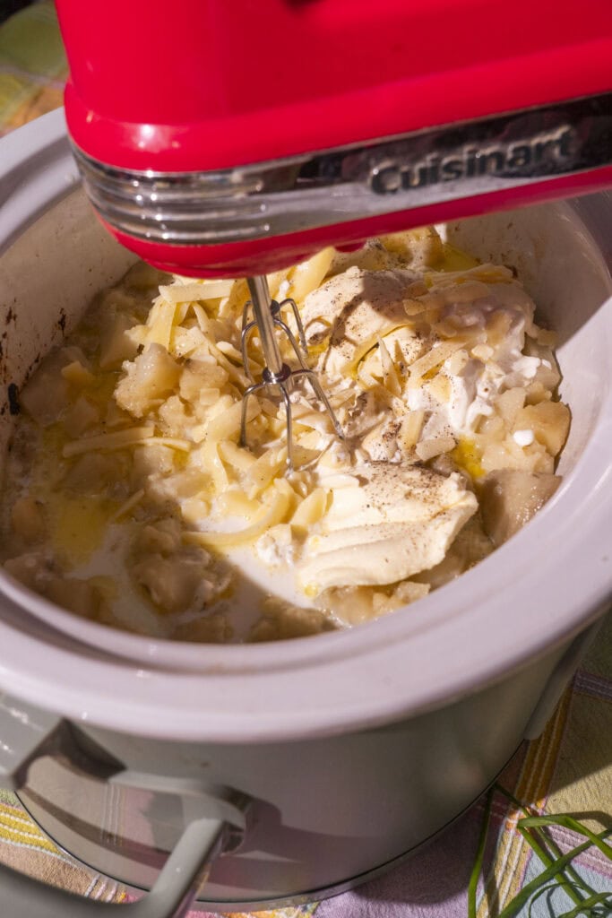 hand mixer mixing ingredients in crockpot.