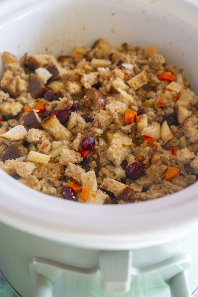 side view of stuffing in crockpot with cranberries and veggies.