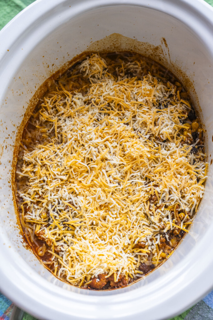 Shredded Mexican-style cheese sprinkled generously over the turkey filling in the slow cooker.