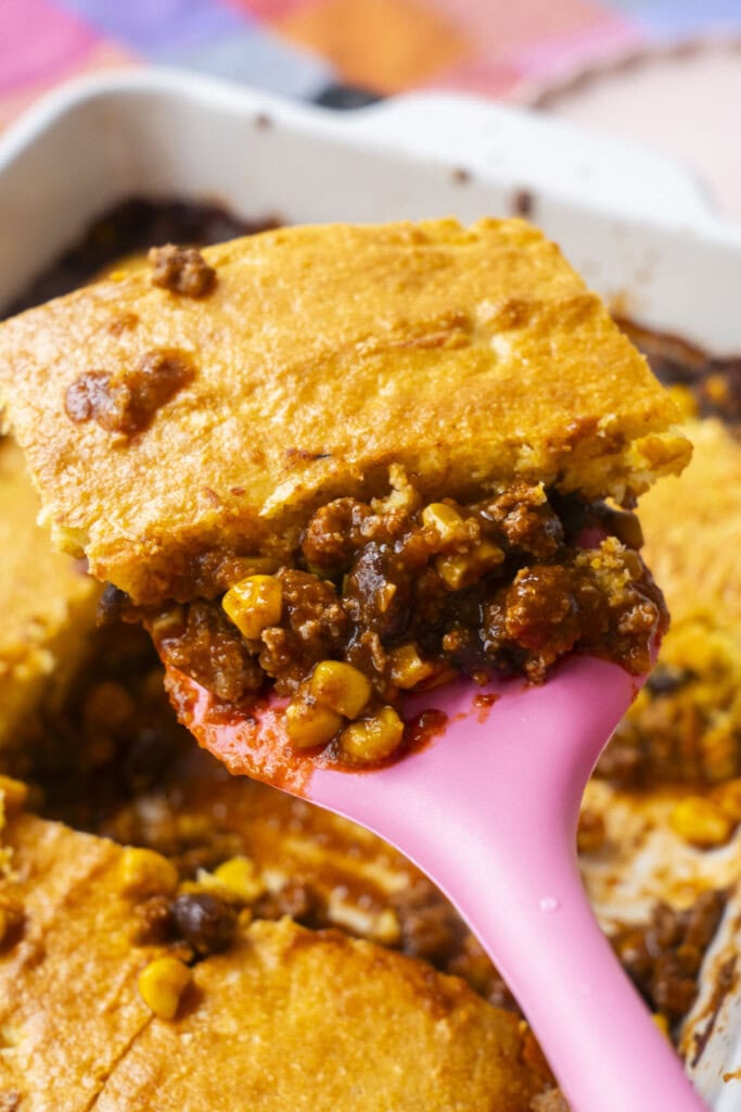 closeup of pink spatula serving casserole.