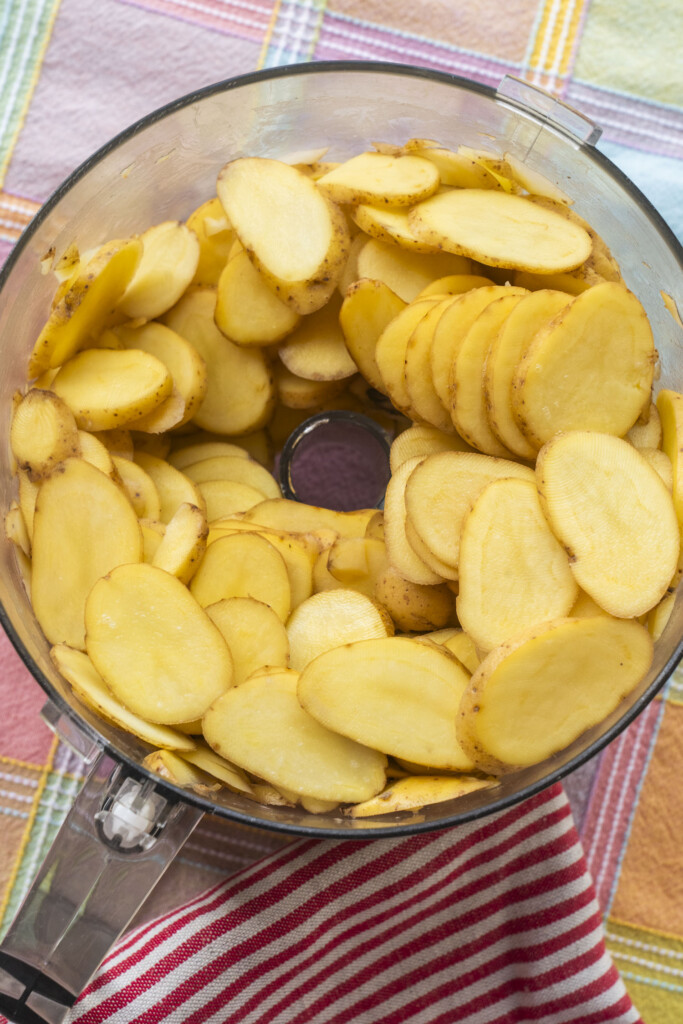 Sliced fingerling potatoes in a food processor bowl, ready for prepping.