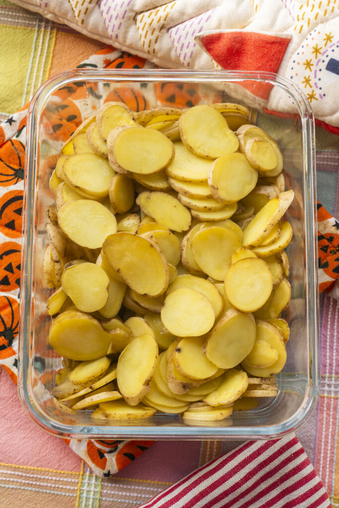 Sliced fingerling potatoes in a glass container, prepped for the casserole.