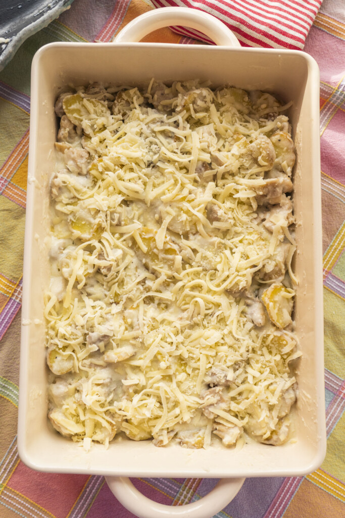 Assembled Chicken Alfredo Casserole topped with shredded mozzarella cheese, ready to bake.