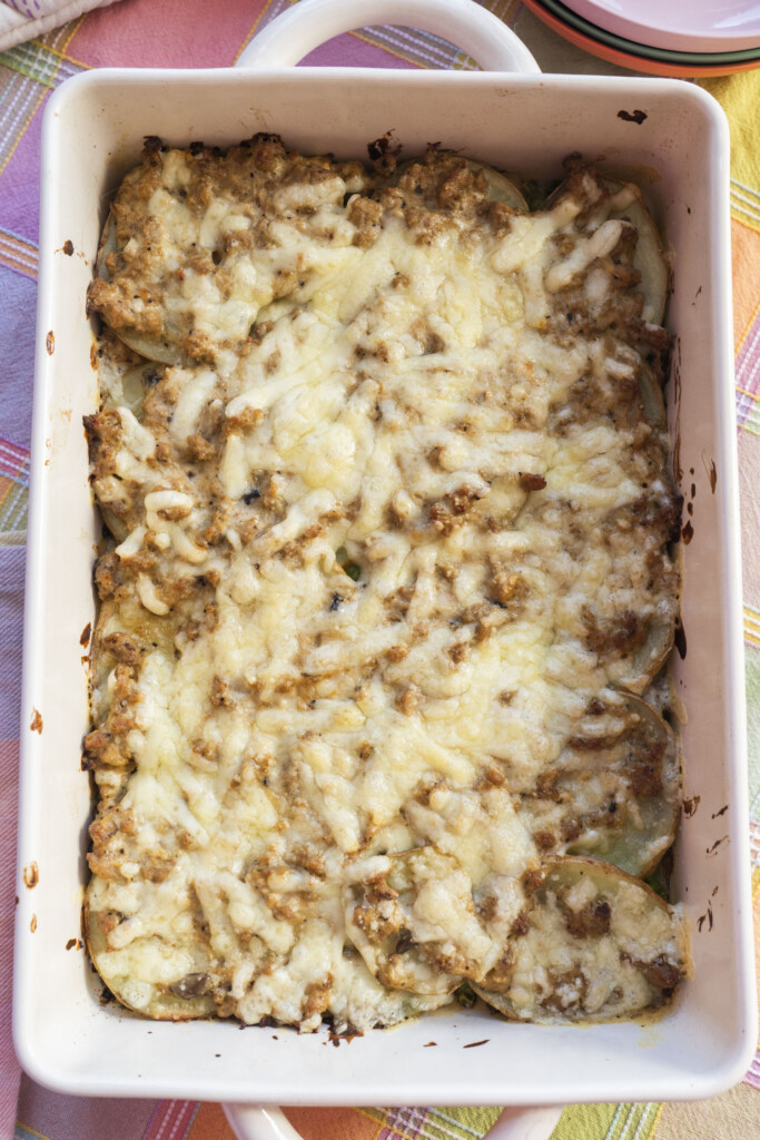 A full, top-down view of a baked Midwest Ground Turkey Potato Casserole in a white rectangular dish, completely covered in a layer of perfectly melted, golden-brown cheese.