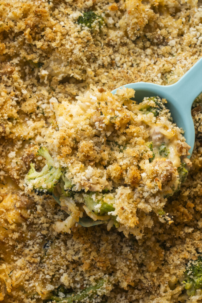 A blue serving spoon scooping out a portion of cheesy Velveeta ground turkey and broccoli casserole.
