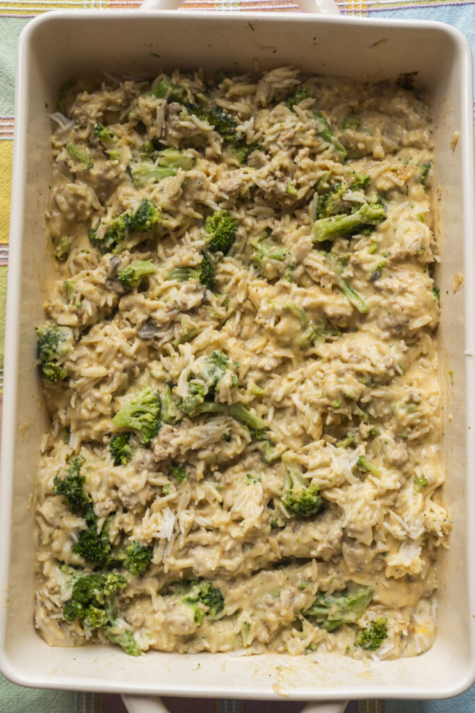 Broccoli, rice, and turkey mixture combined with cheese sauce in a white casserole dish.