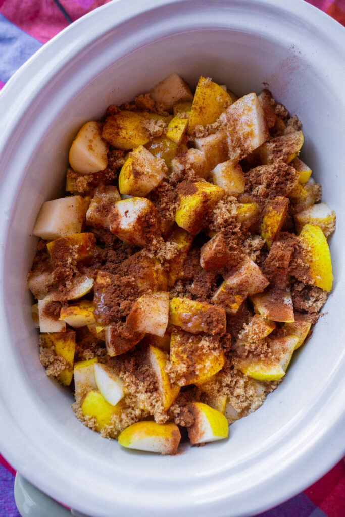 Chopped pears in a slow cooker topped with brown sugar and cinnamon.