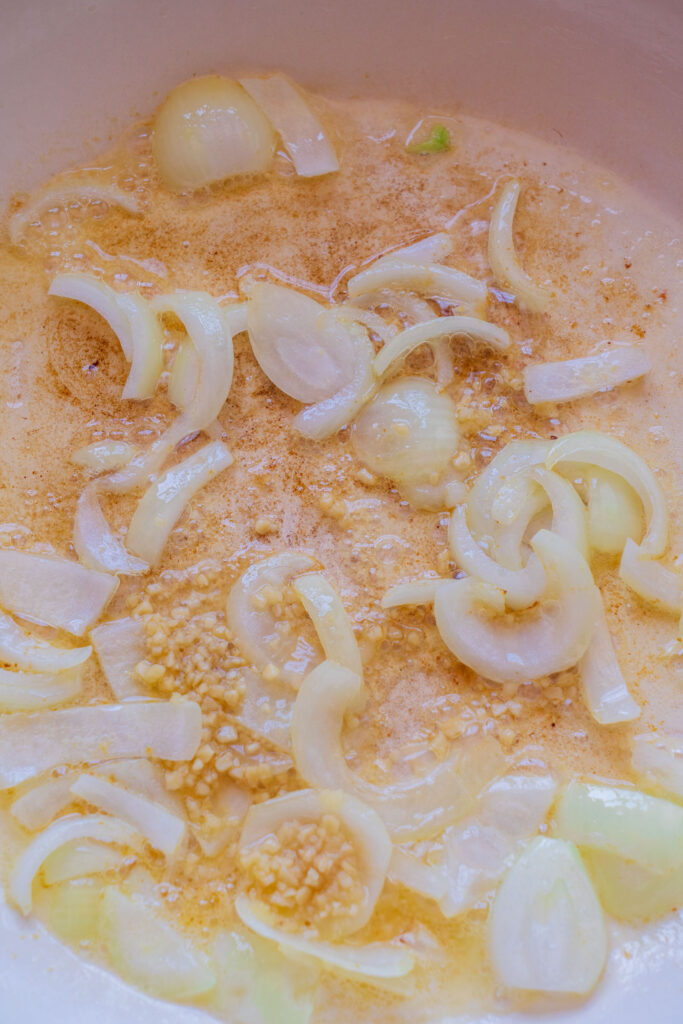 Sliced onions and minced garlic sautéing in oil in a pan.